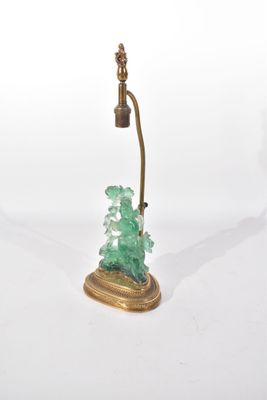 une lampe en verre vert posée sur un pied doré