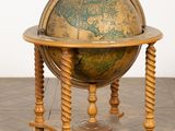un vieux globe posé sur un socle en bois, sur un sol carrelé