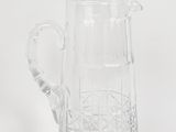 un pichet en verre transparent muni d'une anse, posé sur une surface blanche