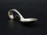 a silver spoon with a curved handle on a black surface