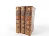 two old books sitting on top of each other on a white surface