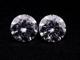 a pair of round brilliant cut diamonds on a black background