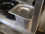 several pans and pans on a metal shelf in a kitchen