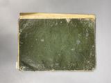an old book sitting on top of a table covered in green paper