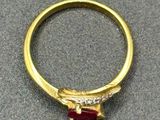 a close up of a gold ring with a red stone on it