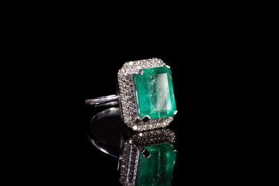 une bague en émeraude et diamant sur une surface noire