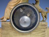 a gold clock with a statue of a woman and a dog on it