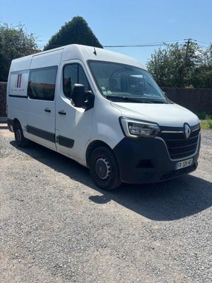 La camionnette blanche est garée sur le parking, à côté d'une clôture.