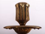 an antique brass candle holder with a candle on top of it