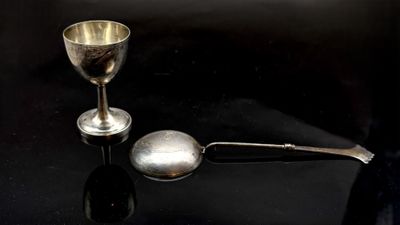 une cuillère en argent et une tasse en argent posées sur une table noire