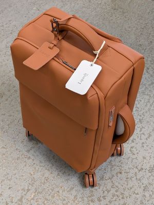 a brown suitcase sitting on the ground with a tag on it