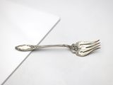 a silver spoon and fork sitting on a white surface