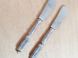 two silverwares on a wooden table with a knife and fork