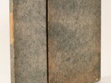 an old book sitting on top of a table next to a white wall