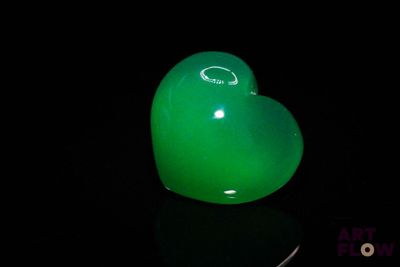 a green heart shaped object sitting on a black surface
