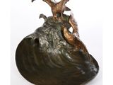 sculpture en bronze représentant deux oiseaux perchés sur un rocher au milieu de l'océan