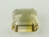 un gros plan d'une pierre de quartz vert facettée posée sur une surface blanche