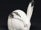a white rabbit figurine sitting on top of a black surface