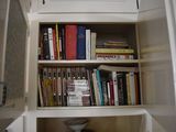 a book shelf with many books on it in the corner of a room