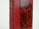 un vieux livre à la couverture rouge posé sur une surface blanche