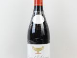 une bouteille de vin posée sur une table à côté d'un mur blanc