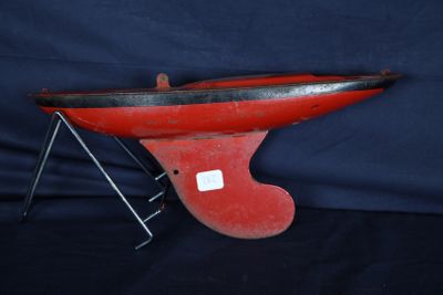 un vieux bateau rouge et noir posé sur un socle métallique