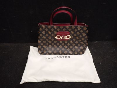 un sac à main marron et rouge posé sur un sac blanc