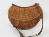 an image of a wicker purse with a leather strap on a white background