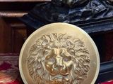 une statue représentant un homme à tête de lion, posée sur une plaque