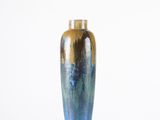 un vase bleu et or posé sur une surface blanche