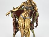 bronze statue of a woman sitting on a chair with her hand on her chin