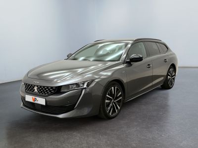 La voiture grise est garée dans une grande pièce au sol noir.