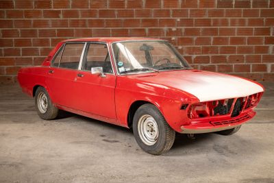 a red car that is parked in front of a brick wall