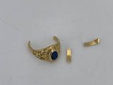 a gold ring with a blue stone sits on a white surface