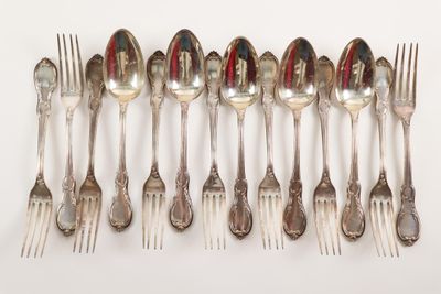 many spoons and forks arranged in a row on a table