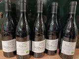 six bouteilles de vin rouge sont alignées sur une étagère