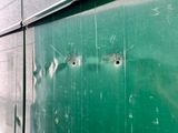 bullet holes in the side of a green bus