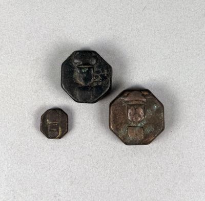 three pieces of metal with a face on them on a white surface