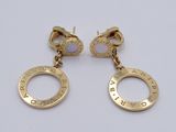 two pairs of gold earrings with pink stones on them on a white surface
