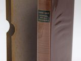 a brown book sitting next to a brown box on top of a white surface