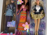 deux poupées Barbie dans une boîte : l'une porte une jupe et l'autre un chapeau