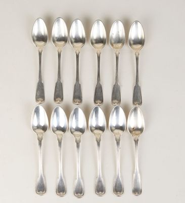 six cuillères en argent sont disposées en ligne sur une surface blanche