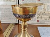 a gold cup on a table with a book in the background