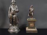 deux statues en bronze représentant un homme et une femme, posées sur un socle