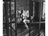 black and white photograph of a naked woman sitting on a couch in a room