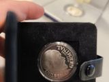 a person holding a silver coin in a black case