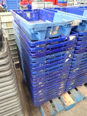de nombreux bacs bleus empilés sur une palette dans un entrepôt