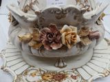 a white vase with flowers on it on a plate