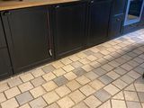 a kitchen with black cabinets and a tile floor