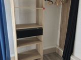 a wooden closet with a shelf and a blue curtain in the corner